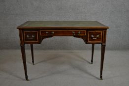 A late Victorian Sheraton style mahogany and satinwood inlaid writing table with a green tooled