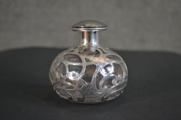 A Victorian glass perfume bottle with a pierced silver overlay in an Art Nouveau inspired design.