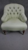 A Victorian walnut tub armchair with a buttoned and curved back on turned legs.