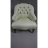 A Victorian walnut tub armchair with a buttoned and curved back on turned legs.