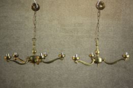 A graduated pair of contemporary brass chandeliers, one with five scrolling arms, the other with