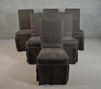 A set of six contemporary dining chairs upholstered in dark grey fabric with skirts hiding the