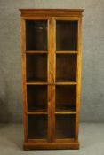 A 20th century ash bookcase, with two glazed doors enclosing shelves on a plinth base. H.190 W.75