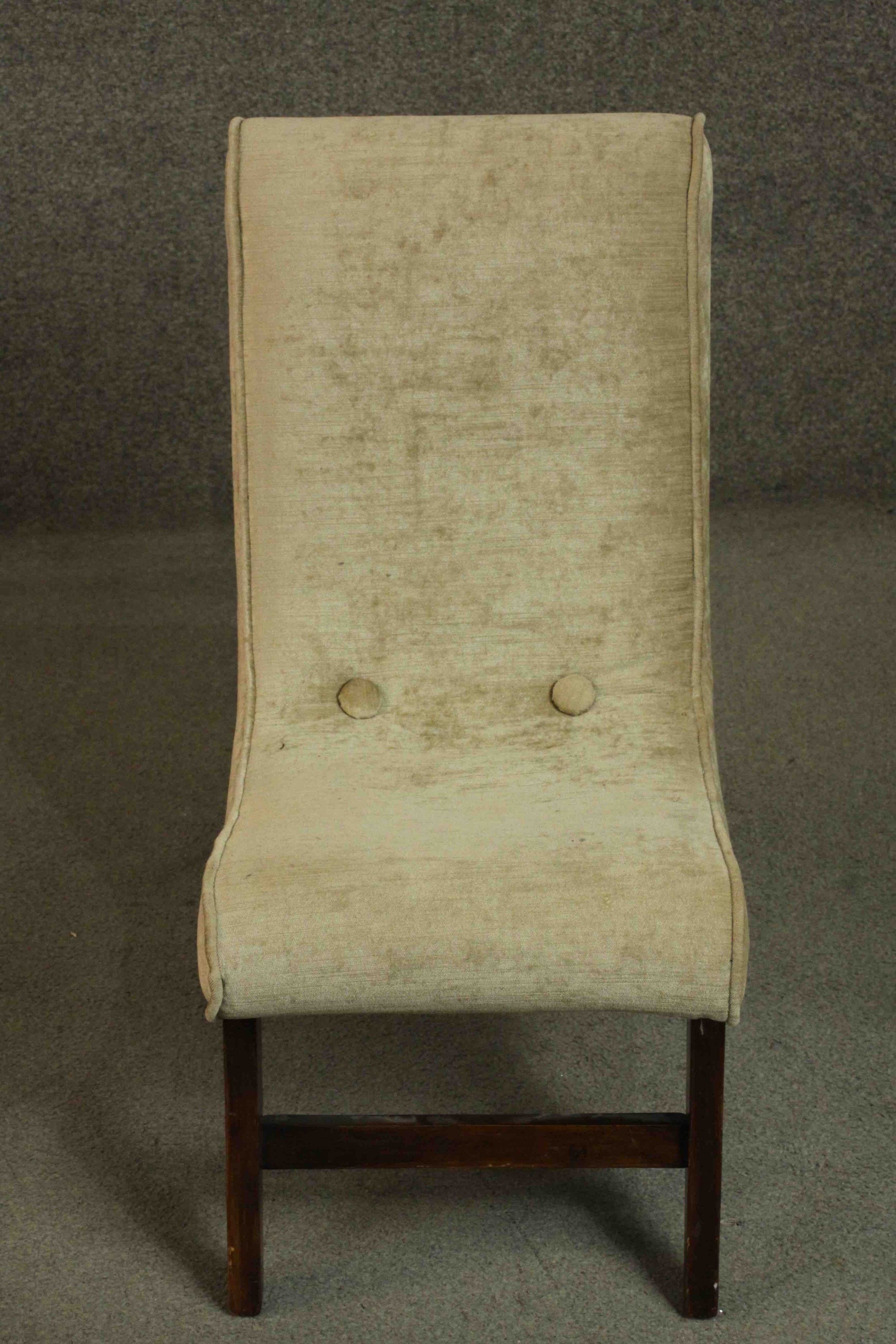 A circa 1960's nursing chair upholstered in gold coloured velour on mahogany legs joined by a