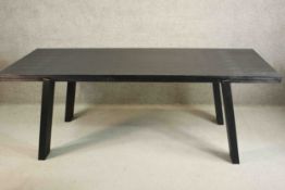 A contemporary ebonised dining table, the rectangular top on splayed rectangular section legs. H.