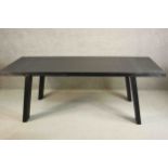 A contemporary ebonised dining table, the rectangular top on splayed rectangular section legs. H.