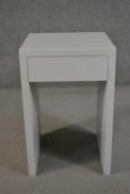 A contemporary white bedside table, of rectangular form with a single frieze drawer on end supports.