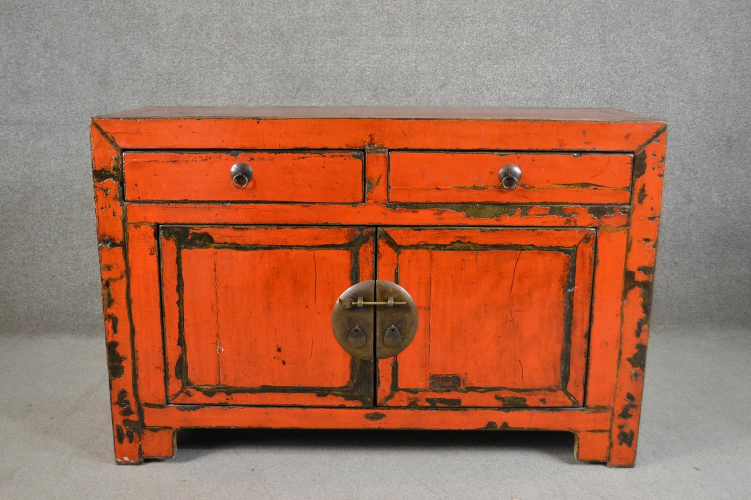 A 20th century Chinese red lacquered sideboard, with two short drawers over two cupboard doors. H.84