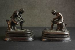 Two 19th century Burmese bronzes, each of a man putting on his sandal mounted on a mahogany base.