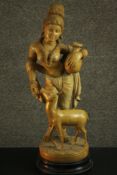 An Indian 20th century carved White Cedar figure of a woman with a deer holding a water vessel. H.62