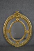 A Victorian gilt framed oval mirror, with a sectional mirror plate in an ornately moulded frame with