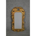 A carved giltwood mirror, the rectangular mirror plate with rounded corners in an ornately carved