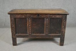 A late 17th/early 18th century oak coffer with a plank top over a panelled body on a carved frame,