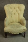 A Victorian mahogany armchair, upholstered in buttoned yellow fabric, on turned legs.