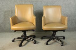 A pair of late 20th century tan leather swivel office chairs, of tub form, with a five point base on