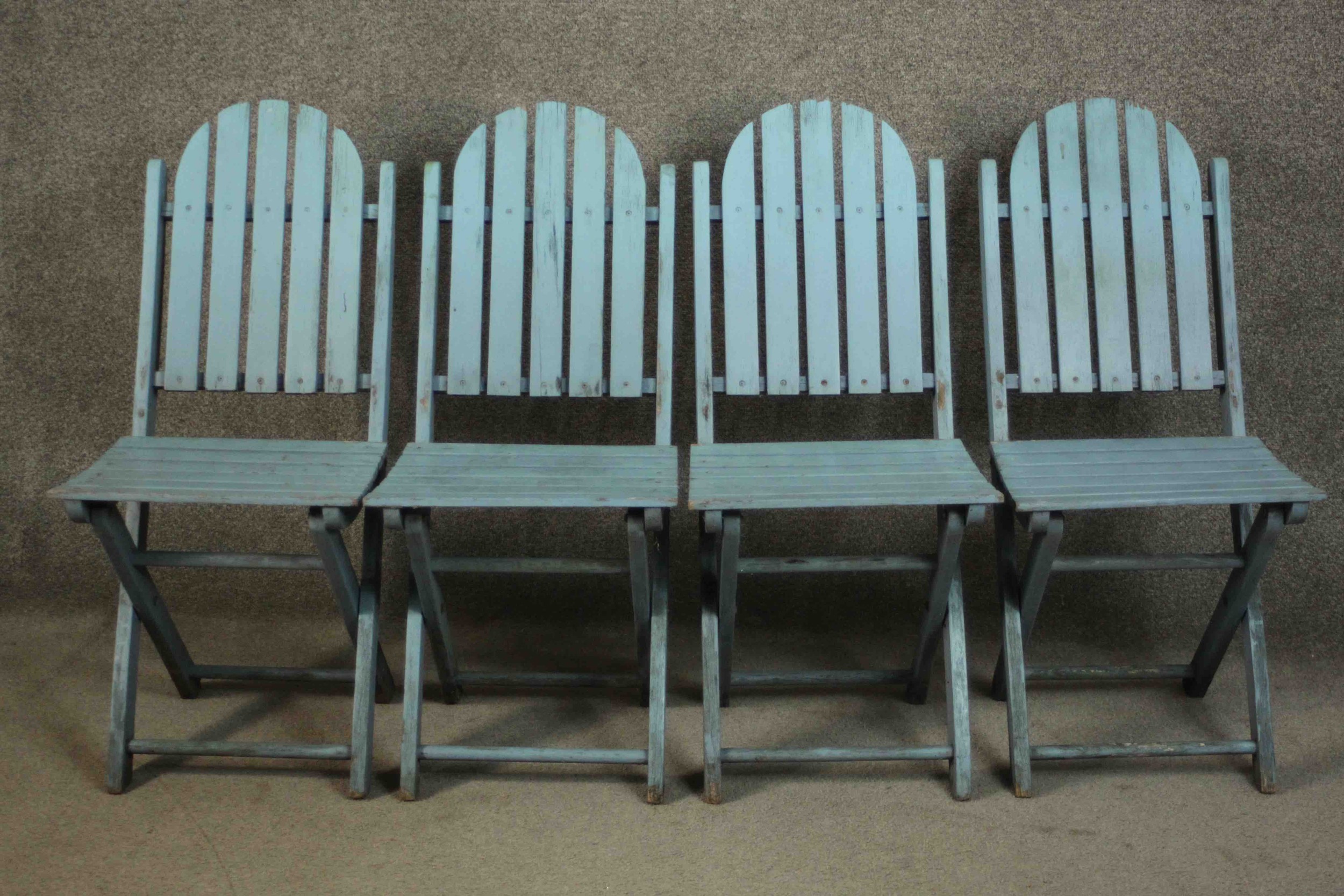 A set of four blue painted folding garden chairs with slatted backs and seats.