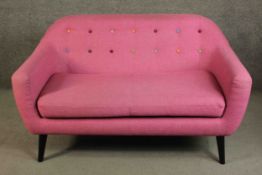 A contemporary Made.com Ritchie sofa, upholstered in pink with a polychrome buttoned back on