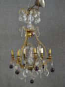 An early 20th century gilt brass six branch chandelier with crystal flowers and drops and purple