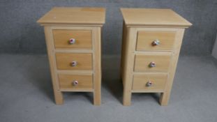 A pair of contemporary oak bedside chests each with three drawers and painted floral handles. H.73