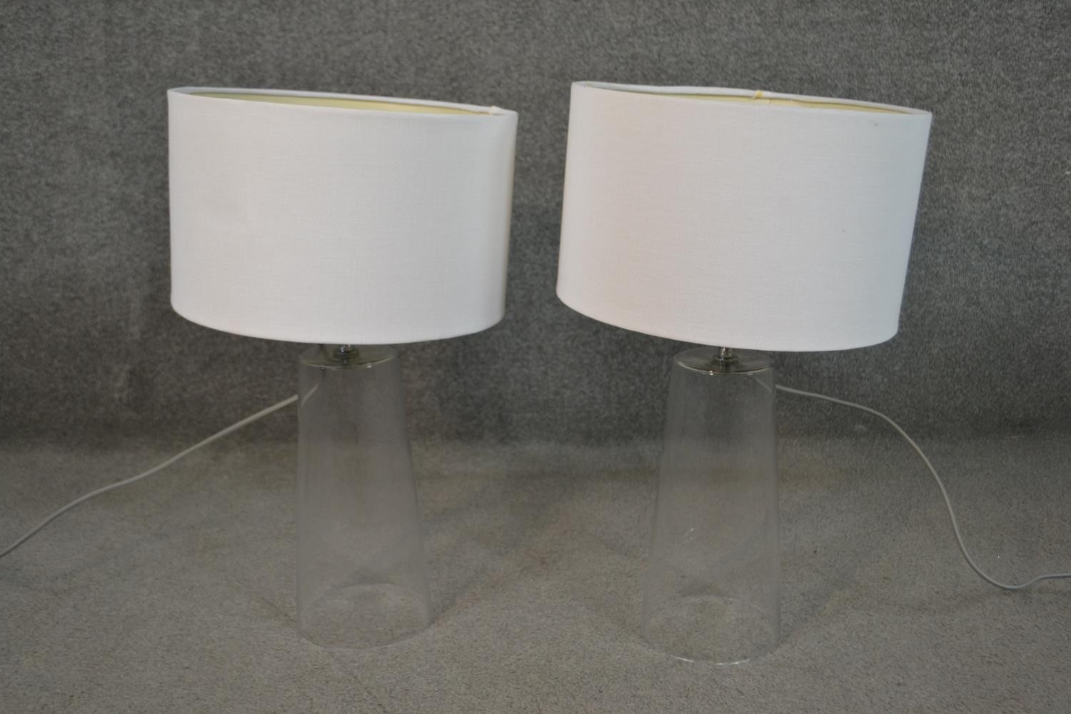 A pair of contemporary glass table lamps of slightly conical form with white shades. H.45cm