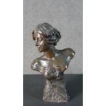An Art Nouveau spelter bust of a lady in a dress on a textured base, indistinctly signed. H.29 W.