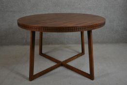 A contemporary circular hardwood dining table, the parquetry top with a blind fret edge on splayed
