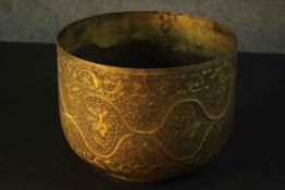 A large 19th century engraved Indian brass bowl decorated with scrolling vines and winged figures.