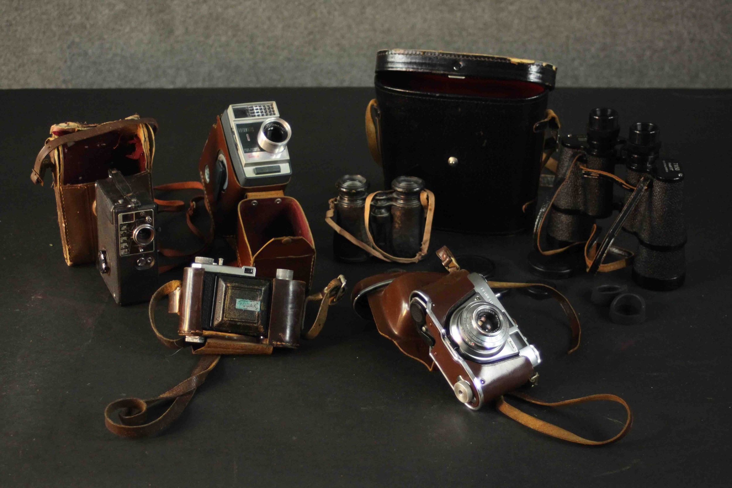 A collection of four vintage cameras. A Kodak Retinette 1A, Kodak Automatic 8, and two pairs of
