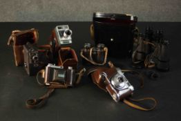 A collection of four vintage cameras. A Kodak Retinette 1A, Kodak Automatic 8, and two pairs of