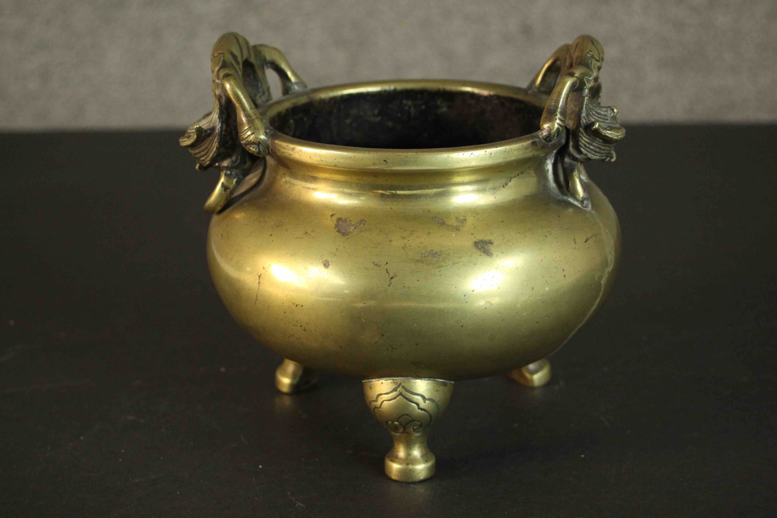 A three footed Chinese brass censer with dragon form handles. Apocryphal Ming Chenghua mark to base.