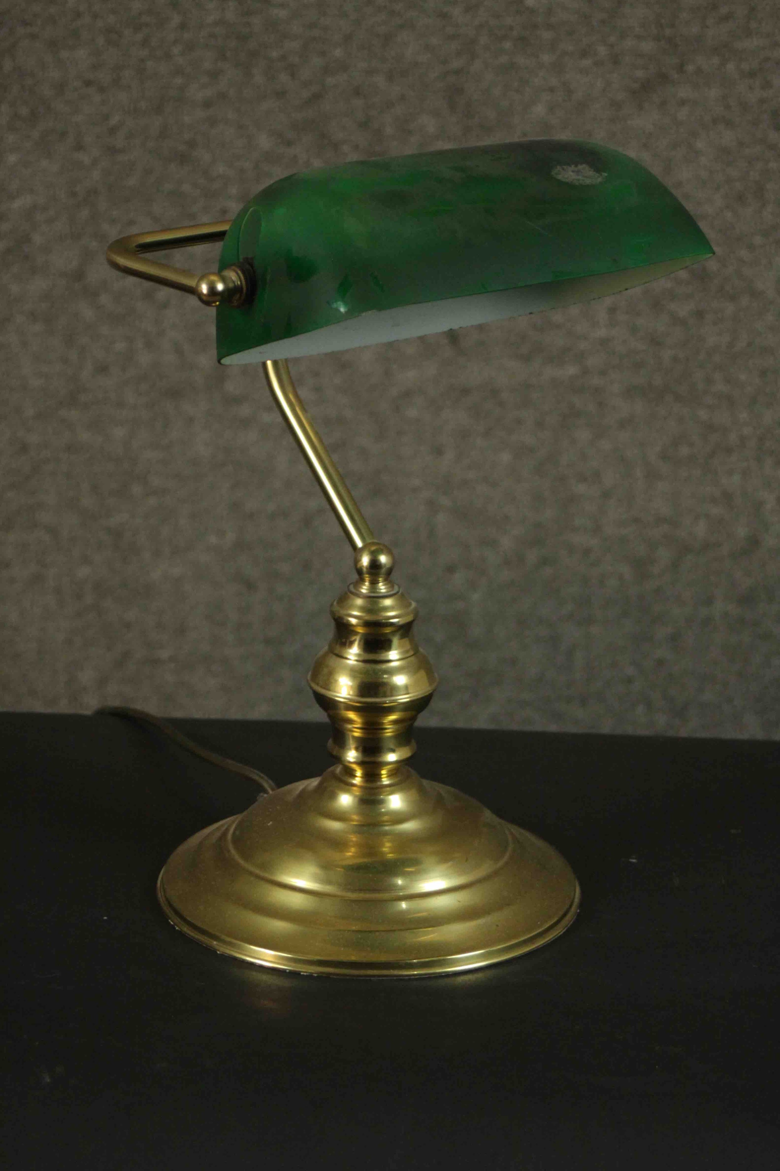 An early 20th century brass banker's desk lamp with green glass adjustable shade and on stepped
