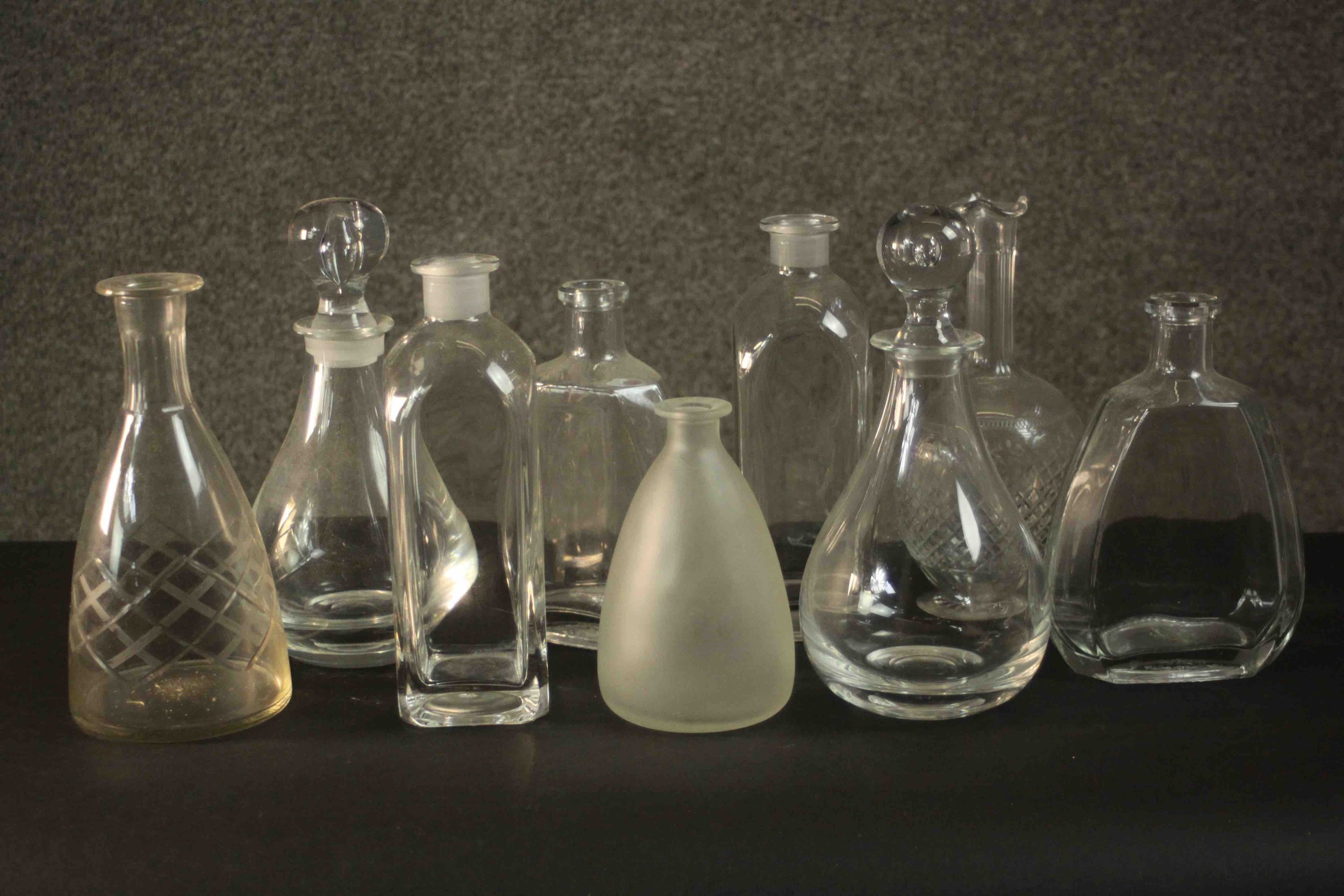 A collection of nine glass decanters, two clear crystal with blown glass stoppers. H.26 Dia.12cm. (