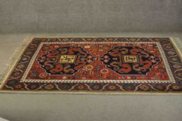 A Indo Heriz rug the central midnight medallions on a rouge ground with flowerhead motifs within