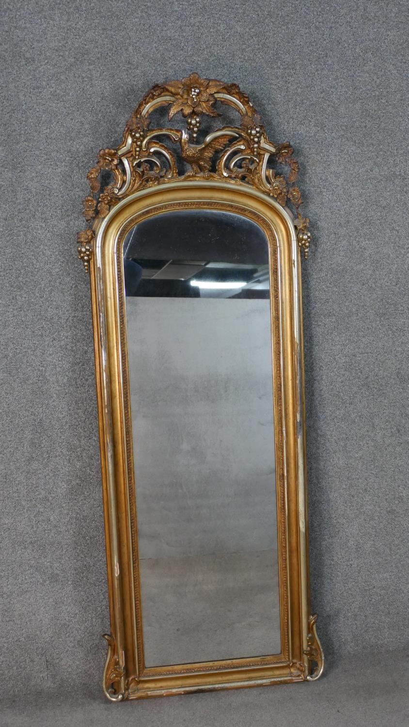 A large early 20th century carved giltwood arched wall mirror. The top with a pierced grape, bird