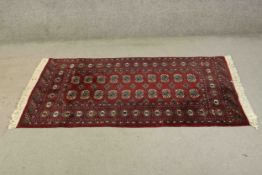 A Pakistan Bokhara with repeating hooked design on a deep red ground within stylised geometric