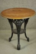 A black painted Victorian cast iron pub table with a circular pitch pine top on three curved legs