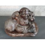 A large Meji period Japanese bronze of a cheerful Hotei reclining against his treasure sack, one