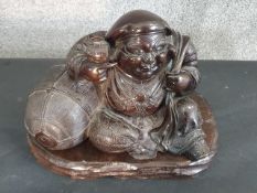 A large Meji period Japanese bronze of a cheerful Hotei reclining against his treasure sack, one