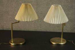 A pair of brass adjustable reading lamps, on circular bases with pleated shades. H.54cm (each)