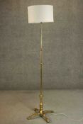 An Arts and Crafts brass floor lamp with a four prong base and floral motifs. H.192cm.