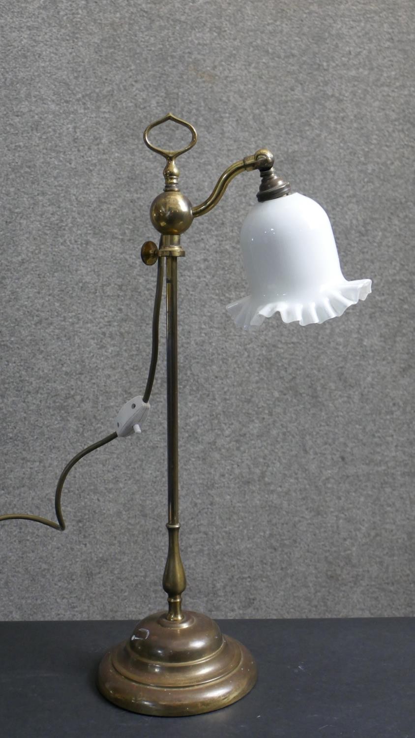 An early 20th century brass student's lamp with handle on a moulded circular base. The bell form
