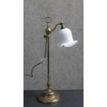 An early 20th century brass student's lamp with handle on a moulded circular base. The bell form