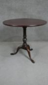 A George III mahogany tilt top tripod table with a circular top on a turned and wrythen stem with
