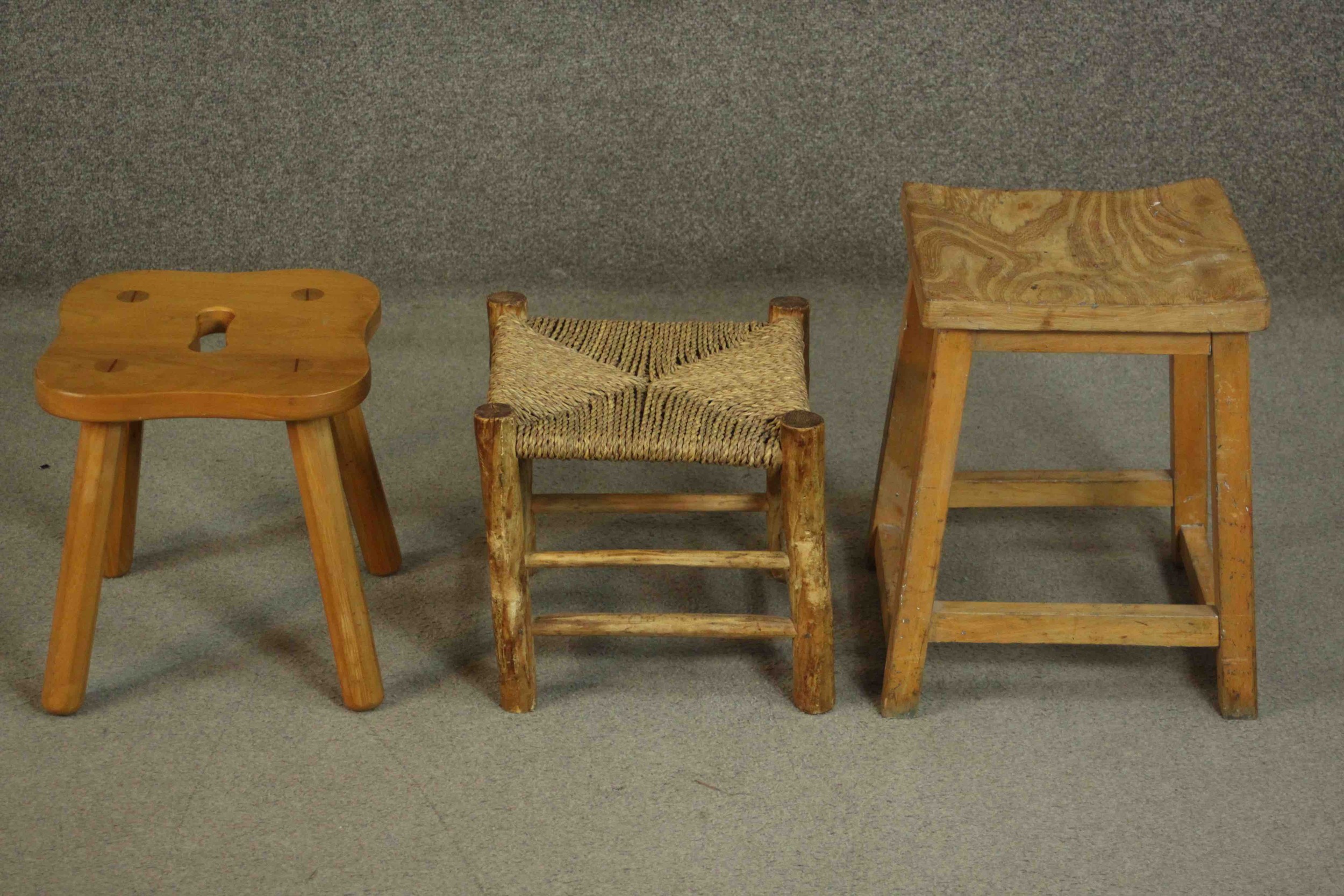 A collection of three stools, including an elm example with a shaped seat and hand hole, a stool
