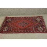 A Persian Shiraz the central medallion with stylised floral motifs on a burgundy ground within