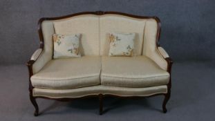 A late 20th century French show wood two seater sofa, with a carved frame, upholstered in cream