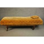 A Victorian daybed or doctor's examining bed, upholstered in a patterned mustard fabric with a loose