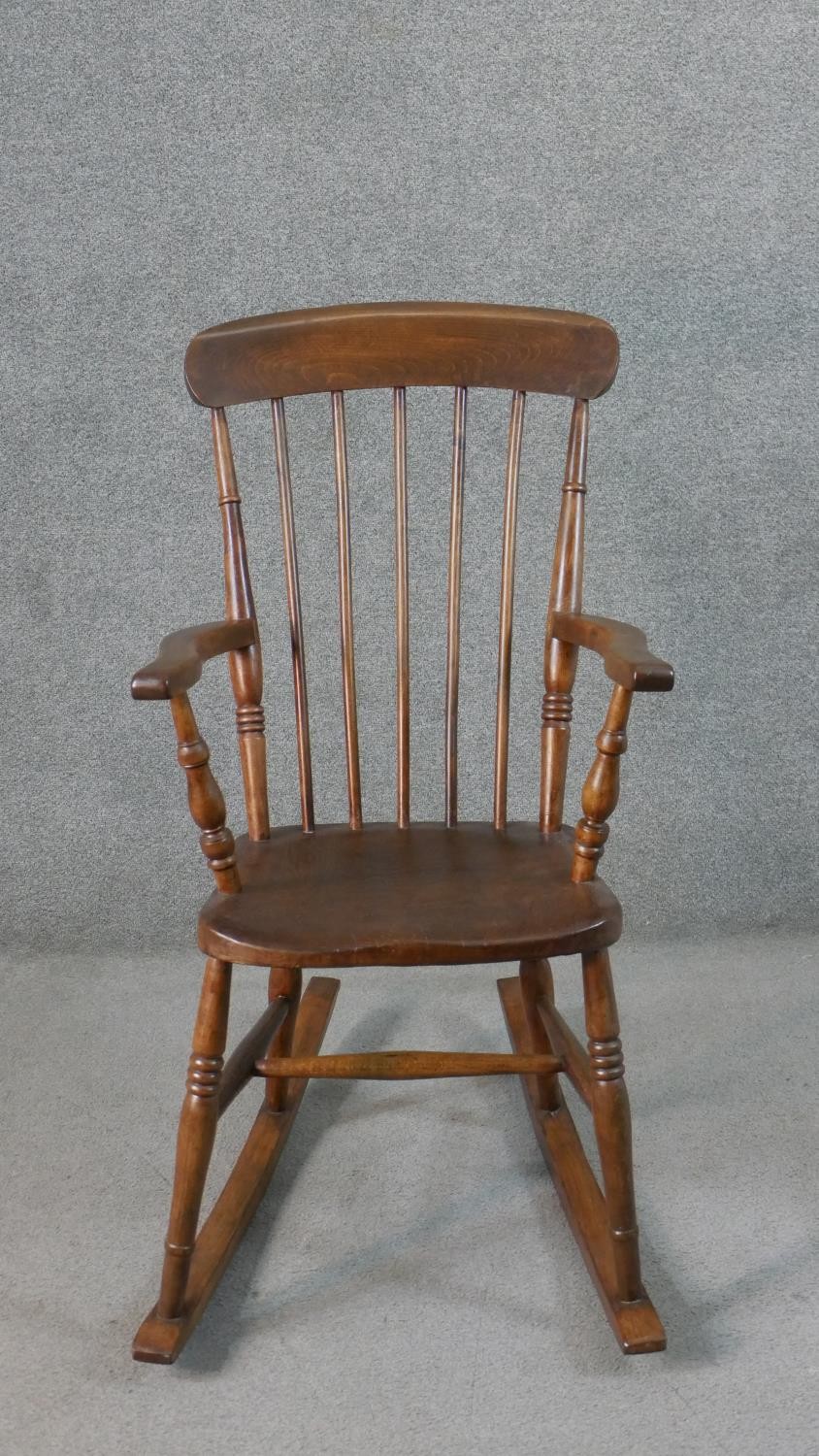 A 19th century style comb back rocking chair, with an elm seat, on turned legs joined by stretchers.