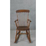 A 19th century style comb back rocking chair, with an elm seat, on turned legs joined by stretchers.