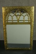 A Gothic Revival/Arts & Crafts planished brass framed mirror with gothic tracery to the rounded arch